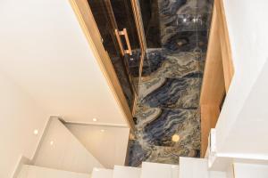 La salle de bains est pourvue d'un sol en marbre et d'escaliers. dans l'établissement Apartman Aries, à Vračar (historical)