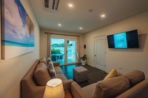 Lux Villa's by GG في شاطئ بالم إيغل: غرفة معيشة مع أريكة وتلفزيون بشاشة مسطحة