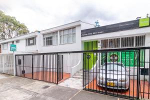 a white building with a gate with a car in it at Hotel Quintas de Normandia in Bogotá