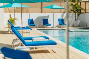 a swimming pool with blue lounge chairs and umbrellas at Lux Villa's by GG in Palm-Eagle Beach