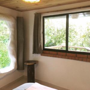 een slaapkamer met een raam en een houten kruk bij Finca Flora del Rio, Habitacion Las Orquideas in Pijao