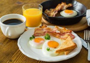 a plate of eggs and bacon and toast with a cup of coffee at Ivanhoe Hotel Motel in Ivanhoe