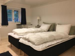 a large bed with white sheets and pillows on it at Tanggården Skoven in Læsø