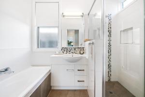 un bagno bianco con lavandino e specchio di Bluestone Cottages - The Shop a Toowoomba Altre 17 foto