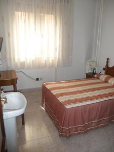 a bedroom with a bed and a sink and a window at Hostal Los Andes in Madrid