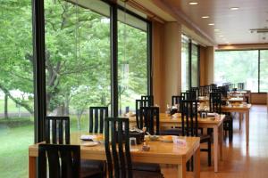 a restaurant with wooden tables and chairs and large windows at Towadako Lake View Hotel in Kosaka