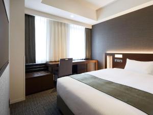 府中市にあるホテル ケヤキゲート 東京府中のベッドとデスクが備わるホテルルームです。
