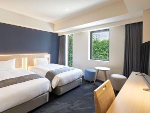a hotel room with two beds and a window at Hotel Keyaki Gate Tokyo Fuchu in Fuchu