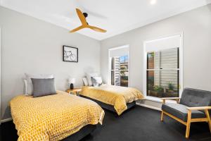 a bedroom with two beds and a ceiling fan at Bluestone Cottages - The Villa in Toowoomba