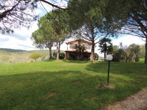 a house on a grassy field with a sign in front at Agriturismo Podere Borgognano in Massa Marittima