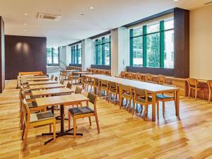 a row of tables and chairs in a room with windows at Hotel Keyaki Gate Tokyo Fuchu in Fuchu