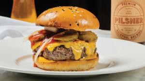 a cheeseburger on a plate next to a beer at Crown Towers Melbourne in Melbourne