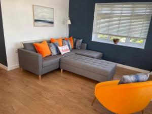 a living room with a grey couch and orange pillows at The Hideout in Anderby