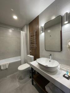 a bathroom with a sink and a toilet and a mirror at Hotel Dastan Aktobe in Aktobe