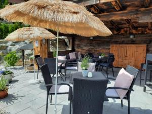 a patio with tables and chairs and a straw umbrella at An der Kaburga in Telfes im Stubai