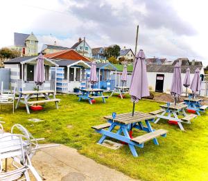 a group of picnic tables with umbrellas on the grass at The Hideout in Anderby