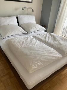 a bed with white sheets and pillows on it at Tor zum Pfälzerwald in Pirmasens