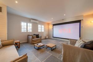 a large screen in a living room with couches and a projection screen at Villa 6Ter Ermitage - Pied dans l'eau in Saint-Gilles-les-Bains
