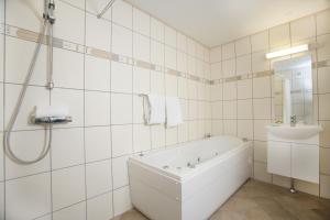 a white bathroom with a tub and a sink at Hotel Strandparken in Holbæk