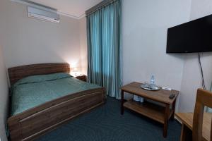 a bedroom with a bed and a table with a television at Hotel Lermontov in Omsk