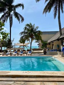 uma piscina com palmeiras e o oceano em Paje Beach Apartments & Hotel em Paje