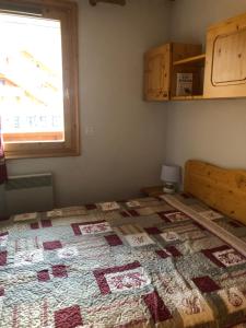 a bedroom with a quilt on a bed with a window at Le Tremplin in Méribel