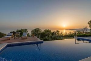 una piscina con puesta de sol en el fondo en Luxury Villa Crystal Blue en Sveti Stefan