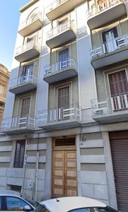 a tall white building with balconies and a wooden door at Abate Luxury Interno 3 in Bari