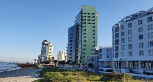 a group of buildings on a beach next to the ocean at Tranquil Impulse on Strand in Cape Town +6 photos