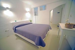 een witte slaapkamer met een paars bed en een wastafel bij Casa Vento - Maisonette near Santa Maria beach in Santa Maria