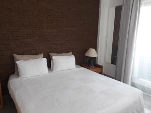 a bedroom with a large white bed with a brick wall at Butikhan Hotel in Gundogan