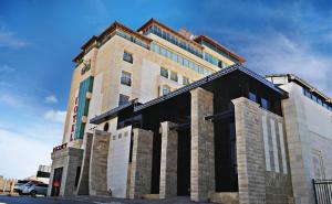 un grand bâtiment en briques sur le côté d'une rue dans l'établissement Regency Hotel Hebron, à Hébron