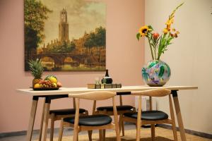 una mesa de comedor con sillas y un jarrón de flores en LOFT 188 Luxury Apartment Hotel en Utrecht