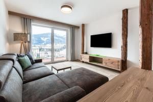 a living room with a couch and a tv at Haus Fellhorn - Ferienwohnungen in Riezlern