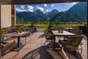 un patio con mesas y sillas con montañas en el fondo en VIER Studios & Restaurant, en Längenfeld