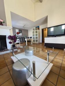 a living room with a glass table and a television at jolie villa avec piscine in Marignane