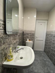 Un baño con lavabo, espejo e inodoro. en Home in batumi, en Batumi