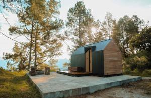 a small cabin with a green roof in the woods at Bobocabin Kaldera, Toba in Parmonangan