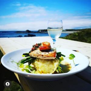 un piatto bianco di cibo con un bicchiere d'acqua di Doonmore Hotel, Bar & Restaurant a Inishbofin