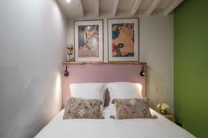 um quarto com uma cama com duas almofadas e fotografias em Boutik Boheme Le jardin Montmartre em Paris
