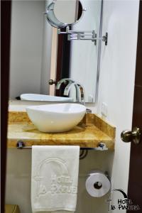 La salle de bains est pourvue d'un lavabo blanc et d'un miroir. dans l'établissement Hotel La Plazuela, à Popayan