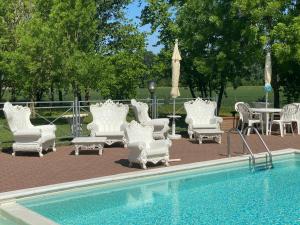 eine Gruppe weißer Stühle und Tische neben einem Pool in der Unterkunft Hotel Luna in San Felice sul Panaro