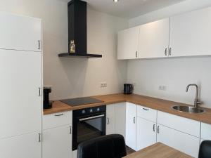 a kitchen with white cabinets and a sink and a stove at Appartement aan de Mergelgrot -Cauberg Valkenburg in Valkenburg