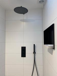 a bathroom with a shower with a tv on the wall at Appartement aan de Mergelgrot -Cauberg Valkenburg in Valkenburg