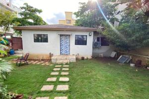 a small white house with a yard with a lawn at Farmhouse in Pune city in Pune +3 photos