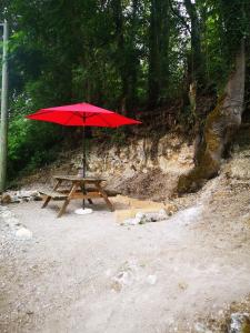 einen Picknicktisch mit einem roten Sonnenschirm am Strand in der Unterkunft chez Pauline & Sébastien le Bien-être proche de la forêt in Saint-Gervais-la-Forêt
