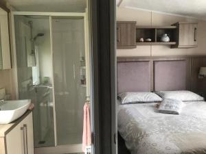 a bedroom with a bed and a shower and a sink at Number 42 @ Lilliardsedge in Jedburgh