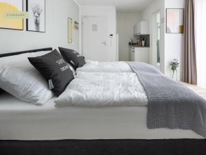 Una cama blanca con almohadas blancas y negras. en limehome Osnabrück Johannisstraße, en Osnabrück