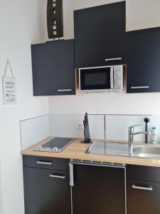 eine Küche mit schwarzen Schränken und einer Mikrowelle in der Unterkunft Ferienapartment Heimatgefühl in Bühl