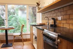 a kitchen with a stove and a table and a window at Peaceful & Central Self Contained 1 Bedroom House in Glastonbury